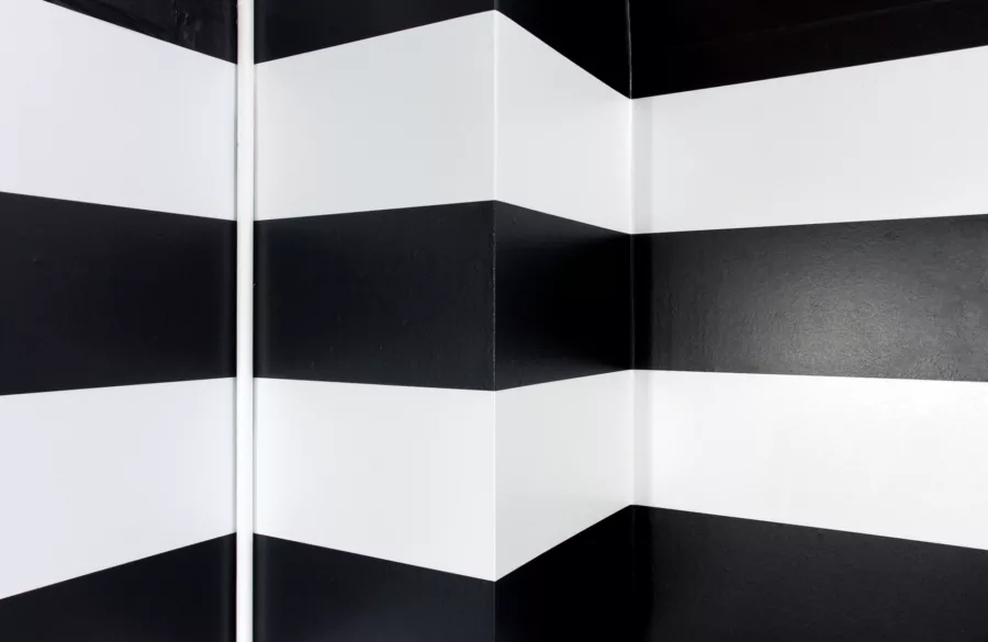 Black and white striped graphic shown distorted across corners in wall.