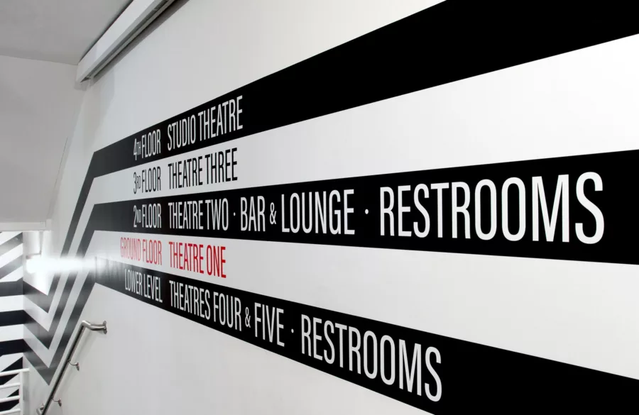 Black and white striped graphic on wall with wayfinding language.