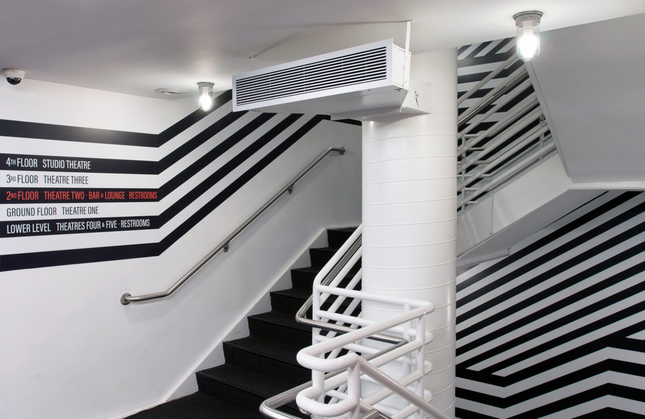 A staircase with a black and white striped design that includes wayfinding for a five-story building.